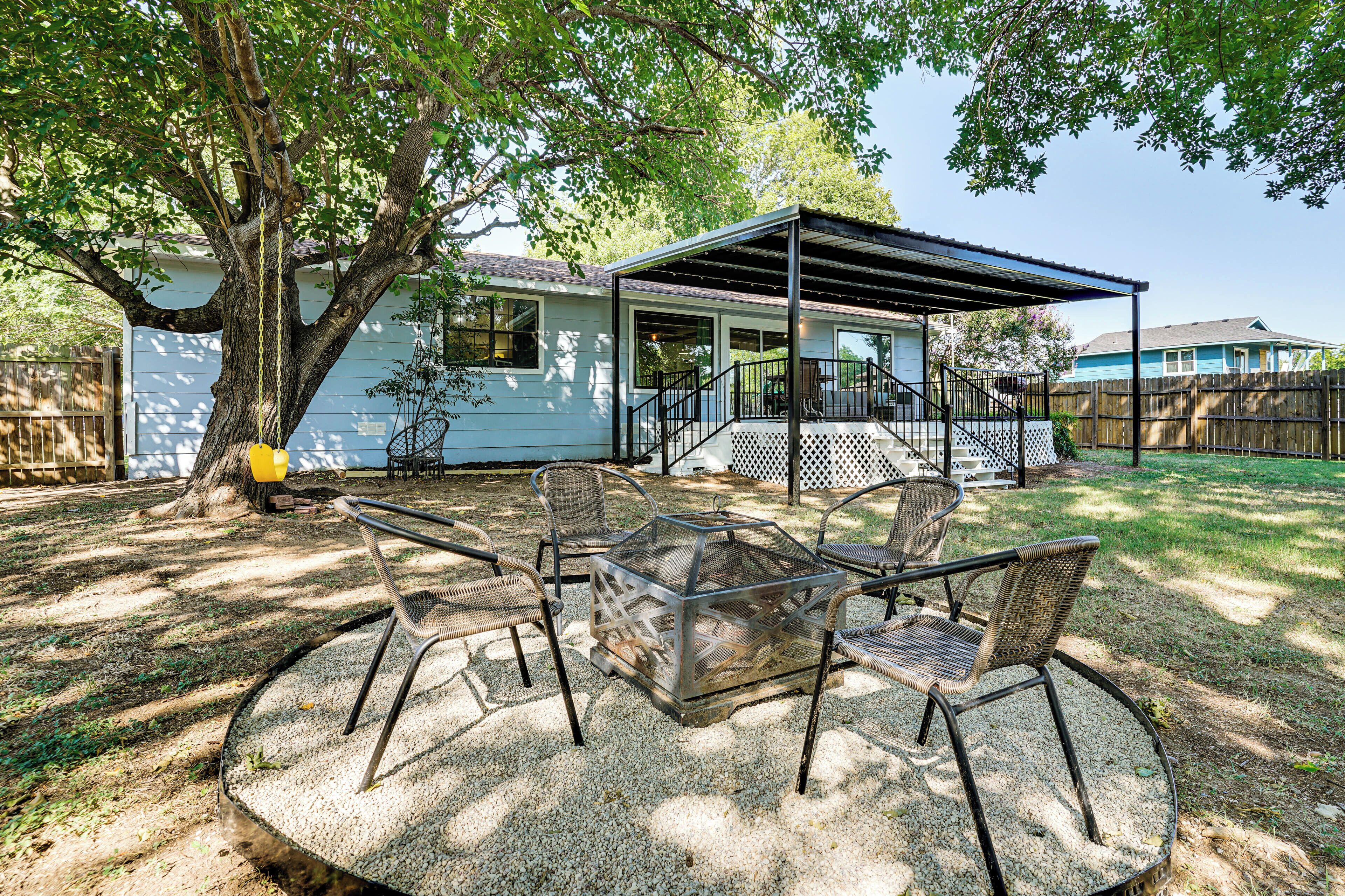 A covered patio with outdoor furniture and a tree providing shade.