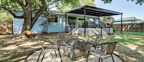 A covered patio with outdoor furniture and a tree providing shade.