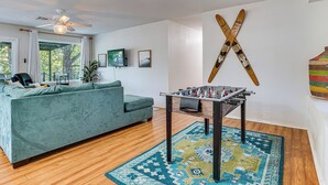A living room with a sofa, a foosball table, and a large window.