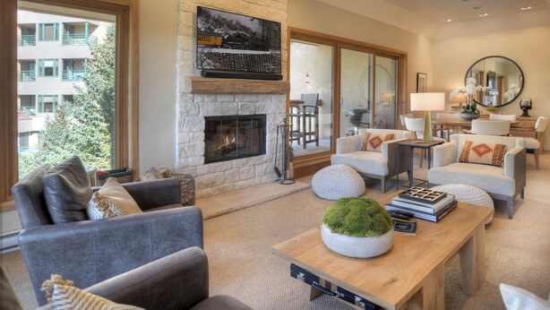 A spacious living room with a stone fireplace, comfortable seating, and a view of the outdoors.