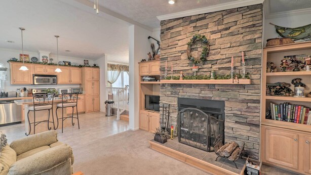 A spacious living area with a stone fireplace, wooden shelves, and a kitchen in the background. - Oakland Retreat ~ 13 Mi to Deep Creek Lake! (Oakland)