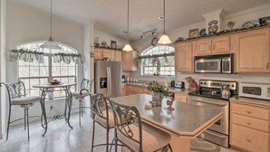A spacious kitchen with a large island, stainless steel appliances, and a dining area with wrought iron chairs. - Oakland Retreat ~ 13 Mi to Deep Creek Lake! (Oakland)