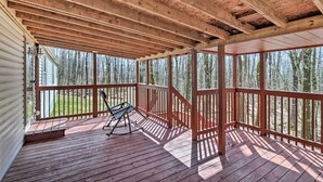 A wooden deck with a rocking chair, surrounded by a wooden railing, overlooking a forested area. - Oakland Retreat ~ 13 Mi to Deep Creek Lake! (Oakland)
