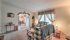 A cozy living room with a plaid sofa, a small table with a lamp, and a doorway leading to another room. - Oakland Retreat ~ 13 Mi to Deep Creek Lake! (Oakland)