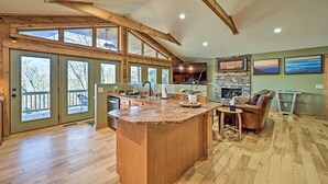Una cocina amplia con una isla grande, vigas de madera y chimenea de piedra.