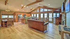 Un amplio salón con suelo de madera, una isla central y un ventanal que proporciona luz natural.