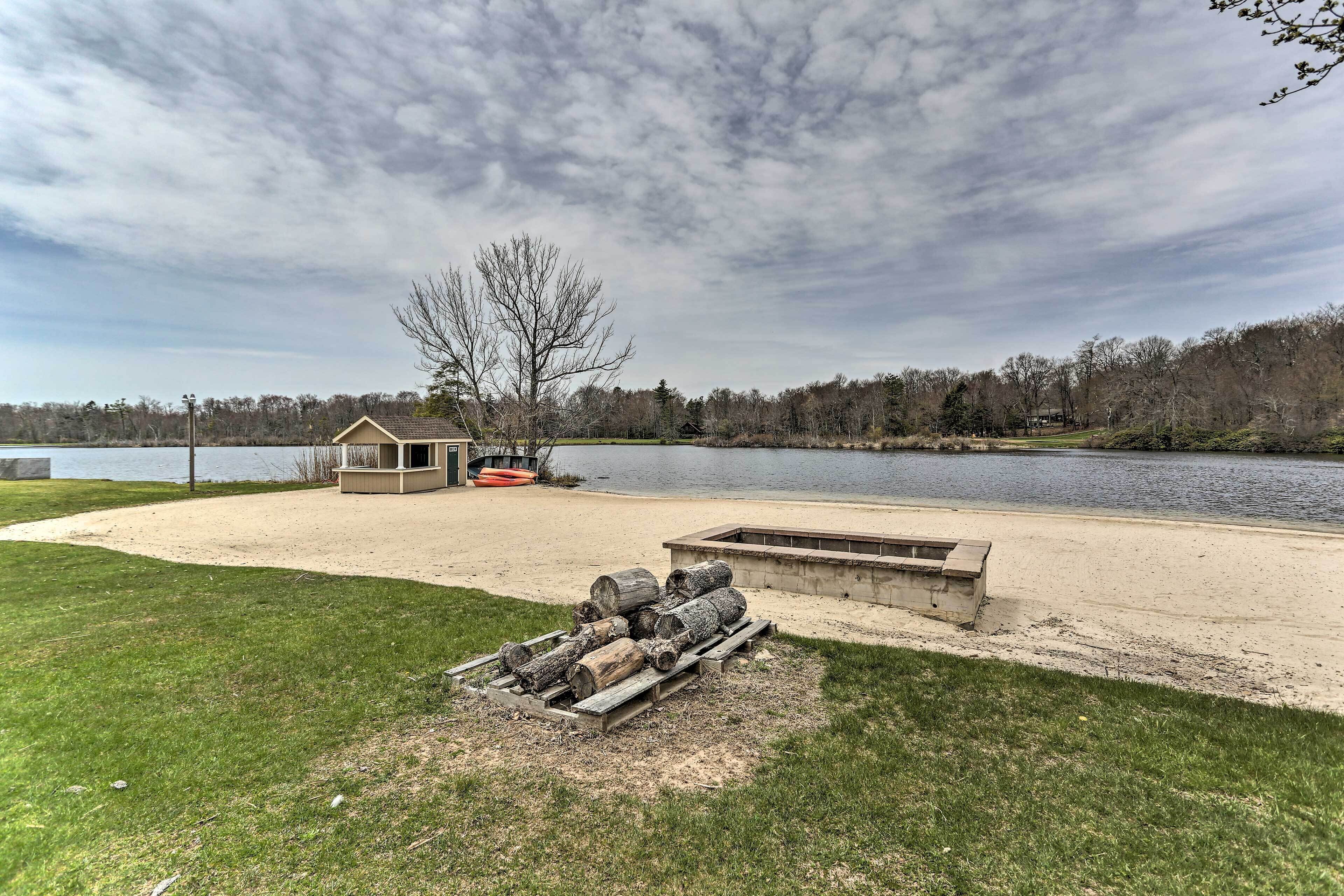 A lakeside property with a sandy beach, a wooden deck, and a small shed.