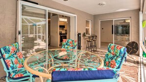 A glass-top dining table with floral chairs, a ceiling fan, and a sliding glass door leading to a kitchen. - Englewood Escape w/ Pool ~ 6 Mi to Beaches! (Englewood)