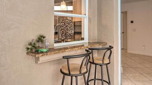 A kitchen with a window, a hanging light fixture, and two bar stools. - Englewood Escape w/ Pool ~ 6 Mi to Beaches! (Englewood)