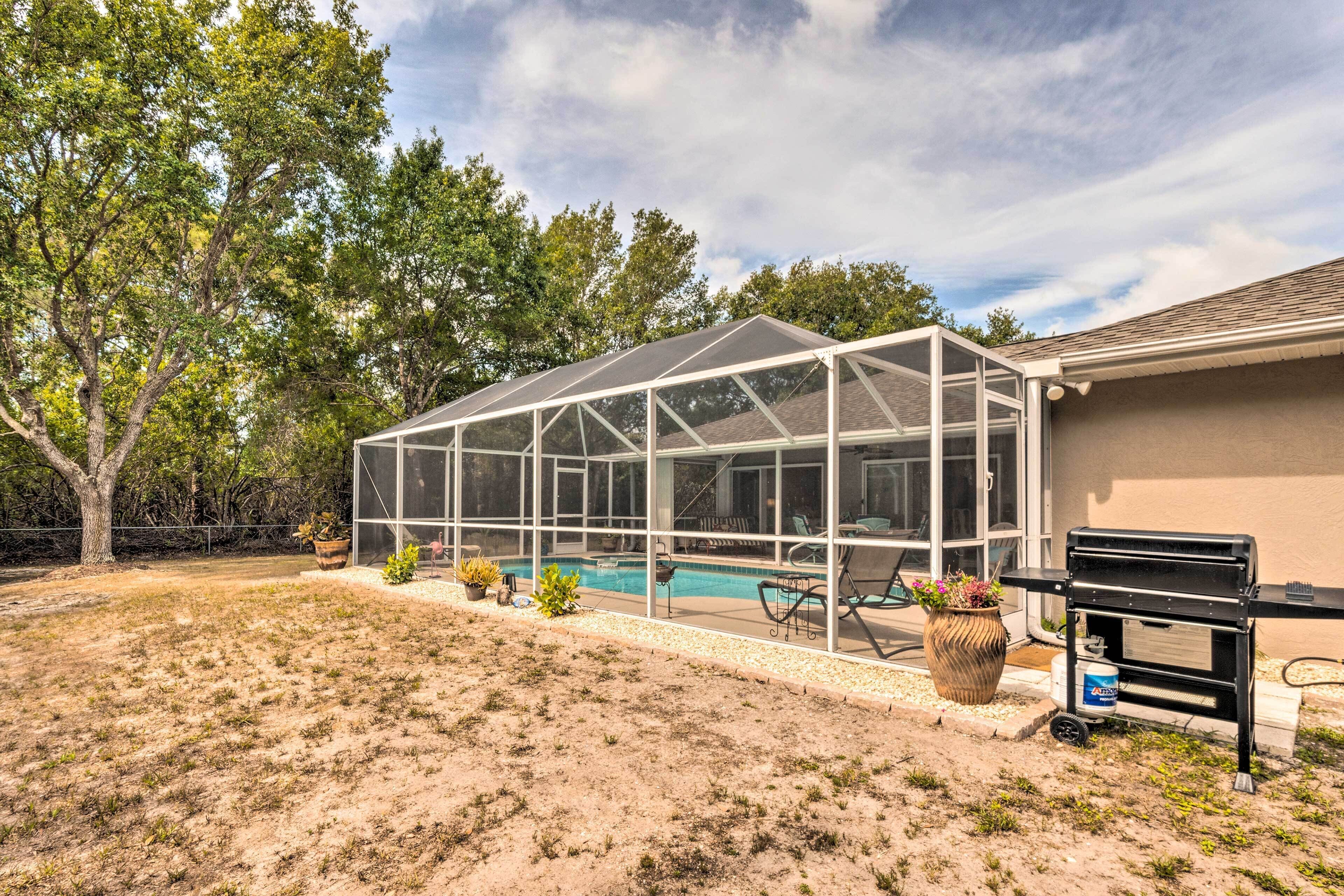 A covered patio with a pool, outdoor furniture, and a grill.