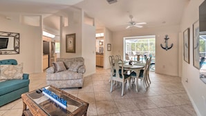 A spacious living room with a sofa, a coffee table, and a dining area with chairs and a table. - Englewood Escape w/ Pool ~ 6 Mi to Beaches! (Englewood)