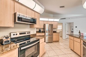 A modern kitchen with wooden cabinets, stainless steel appliances, and a granite countertop.
