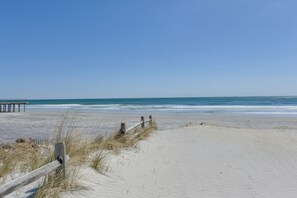 Une plage de sable avec une clôture en bois et un banc.
