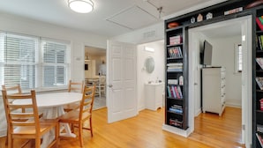 A room with a round wooden table and chairs, a white door, a bookshelf, and a television. - Family-friendly Knoxville Home: Close to UT! (Knoxville)