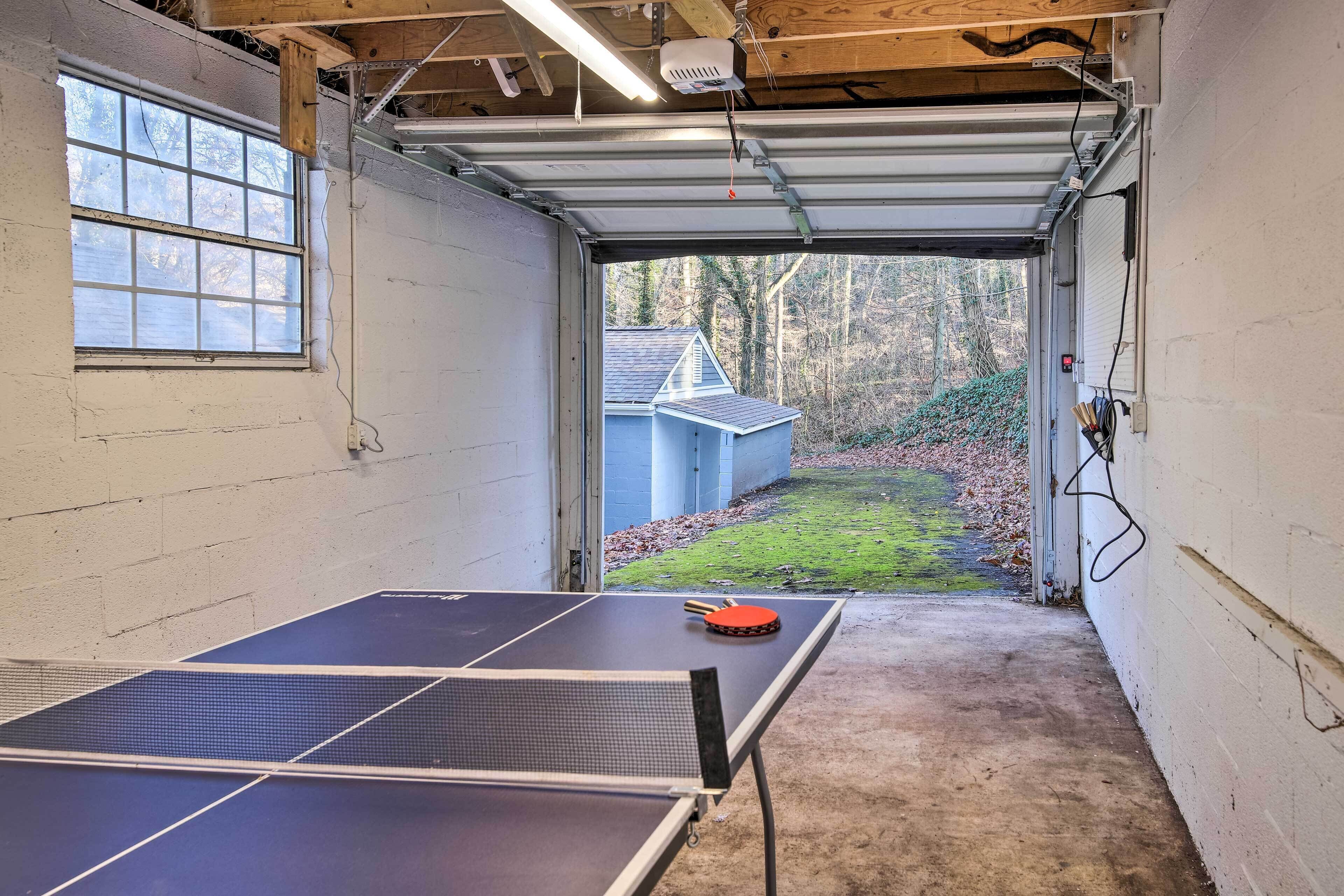Eine Garage mit einem Tischtennisch, einem Fenster und Blick auf ein Haus und Bäume.