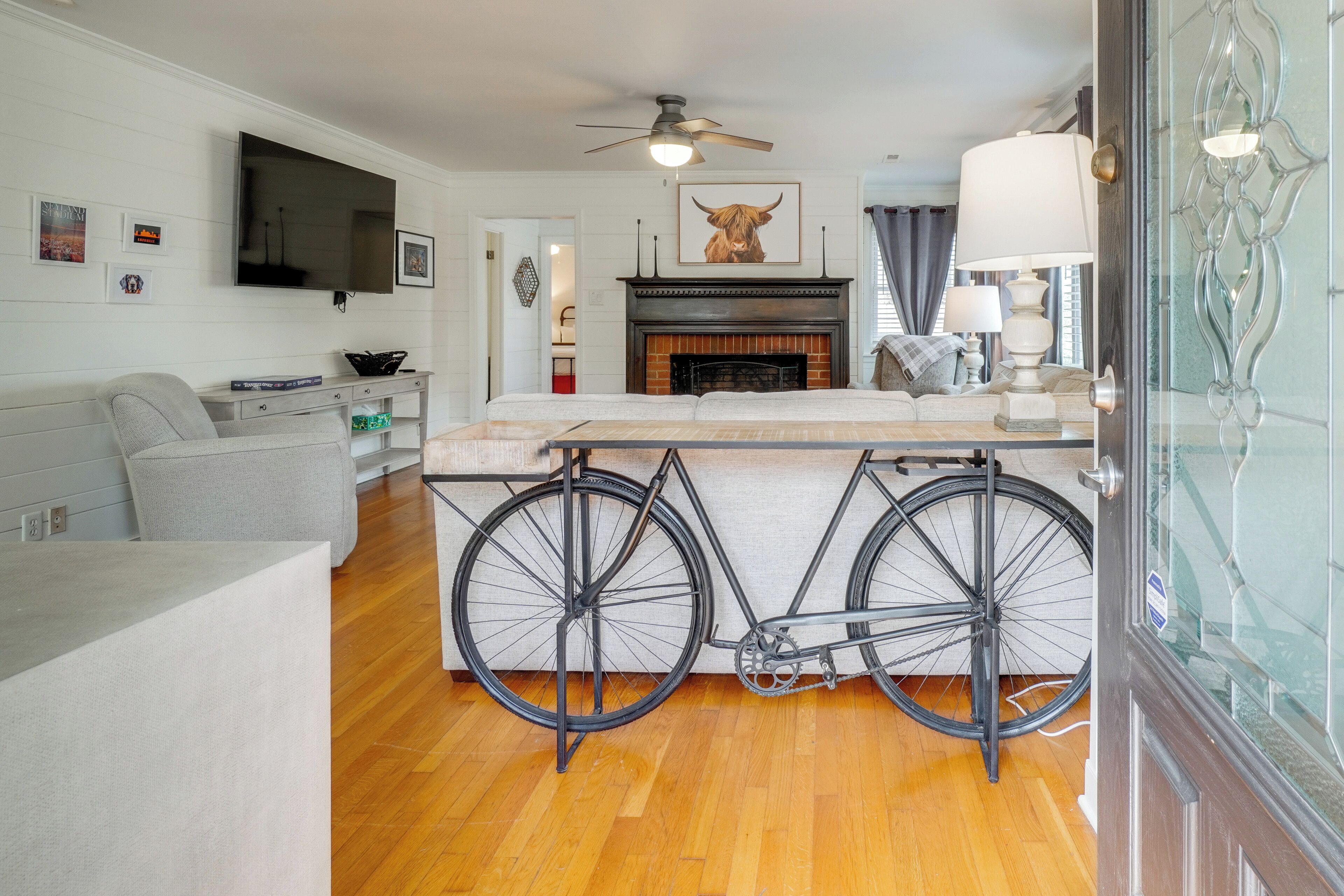 A living room with a fireplace, a mounted TV, and a bicycle.