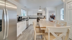 A modern kitchen with white cabinetry, stainless steel appliances, and a wooden dining table. - Family-friendly Knoxville Home: Close to UT! (Knoxville)