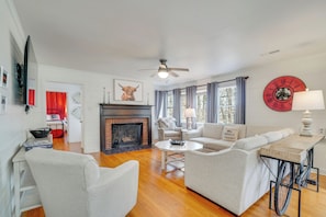 A living room with a fireplace, a ceiling fan, and a large clock on the wall. - Family-friendly Knoxville Home: Close to UT! (Knoxville)