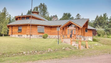 Cozy cabin-style building with a gabled roof and stone foundation, featuring a front entrance and a welcoming porch.