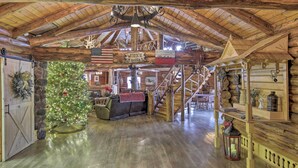 Ein rustikales Blockhaus-Interieur mit Weihnachtsbaum, Holztreppe und verschiedenen Dekorationen.