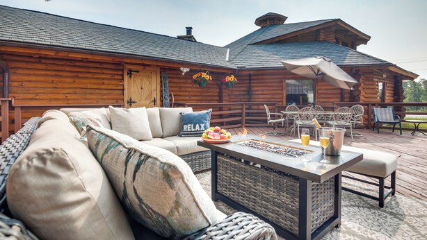 Eine Blockhütte mit einer Veranda, Sitzgelegenheiten im Freien und einem Essbereich mit Tisch und Stühlen.
