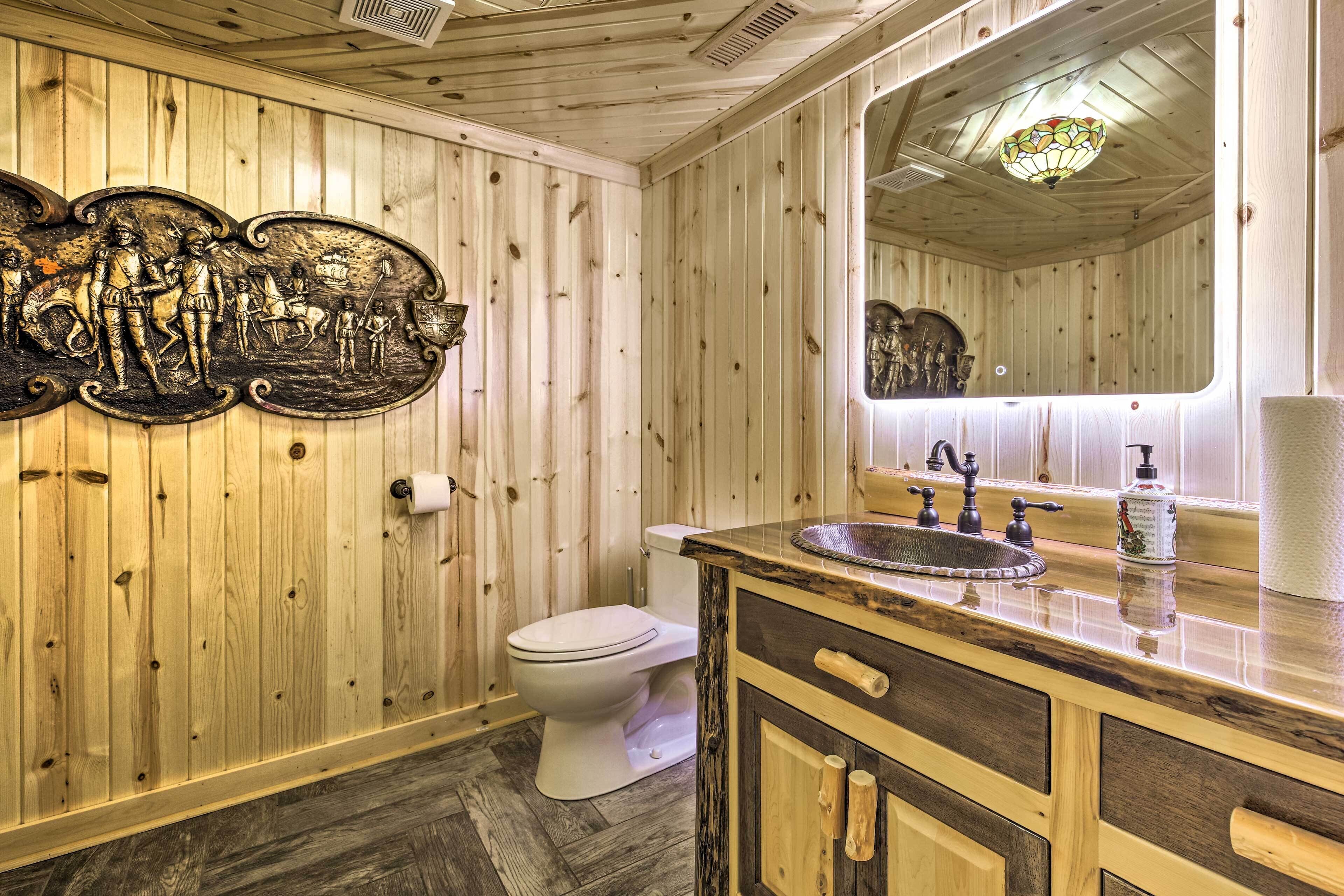Un bagno con rivestimenti in legno, uno specchio grande, un lavandino con un rubinetto d'epoca e un water.