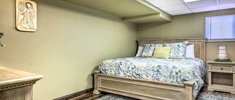 Ein Schlafzimmer mit einem hölzernen Bett, einem Nachttisch, einer Wandskulptur.