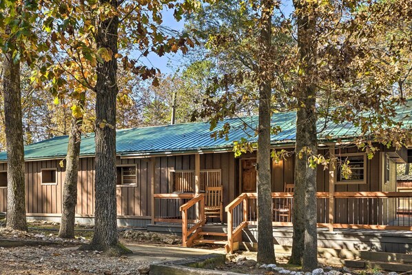 A rustic cabin with a green metal roof, wooden exterior, and a porch with a wooden staircase. - Private Hot Tub & Deck! Broken Bow Group Getaway (Broken Bow)