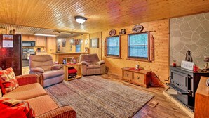 A cozy cabin interior with a wooden ceiling, a fireplace, a kitchen area, and a seating area with a rug. - Private Hot Tub & Deck! Broken Bow Group Getaway (Broken Bow)
