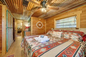A wooden cabin bedroom with a bed, a ceiling fan, and a window. - Private Hot Tub & Deck! Broken Bow Group Getaway (Broken Bow)