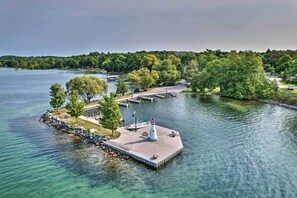 Un phare, par une journée ensoleillée, sur une propriété au bord du lac, avec un quai et un sentier pédestre.