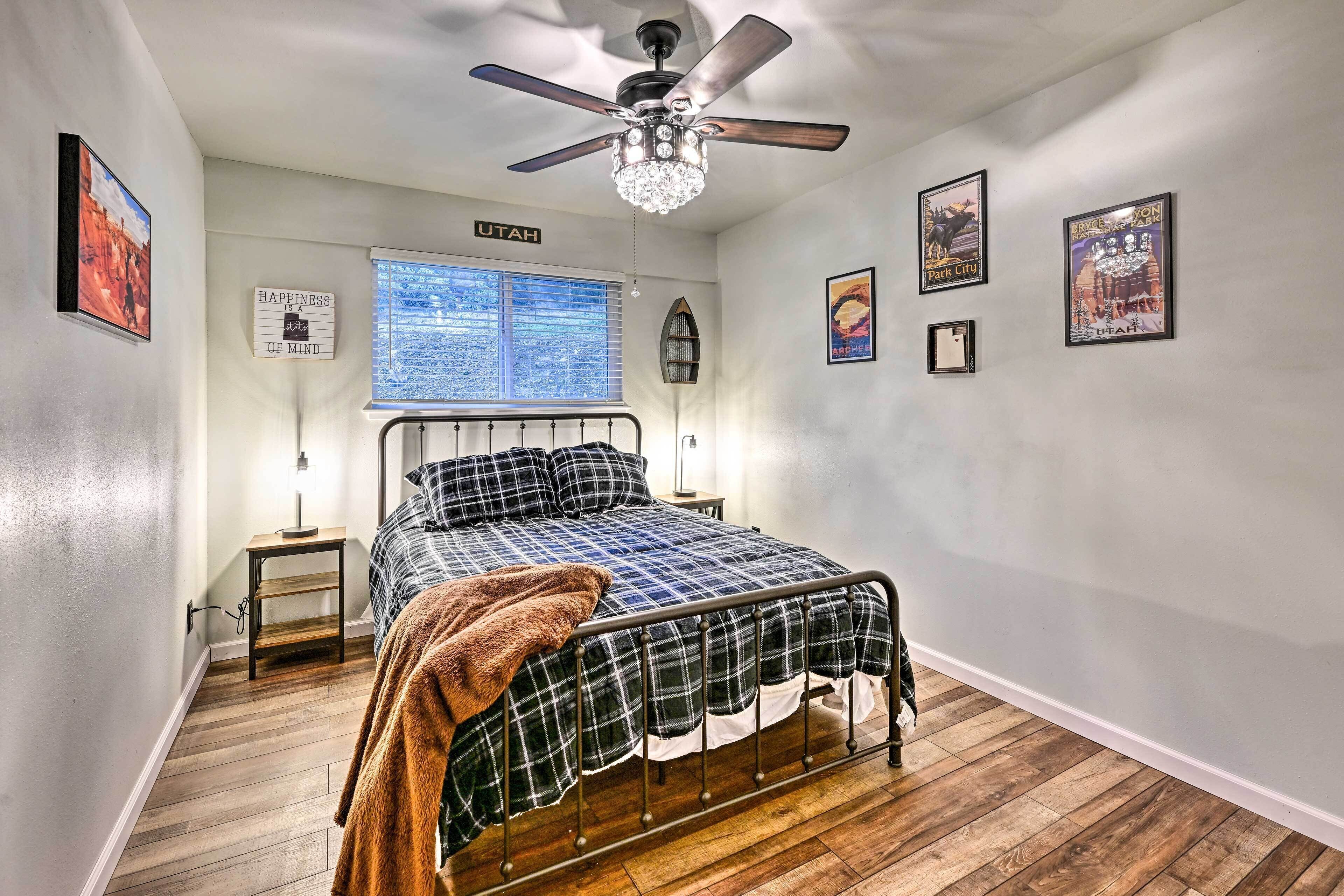 Une chambre à coucher avec un lit, un ventilateur de plafond, une fenêtre et des éléments décoratifs sur les murs.