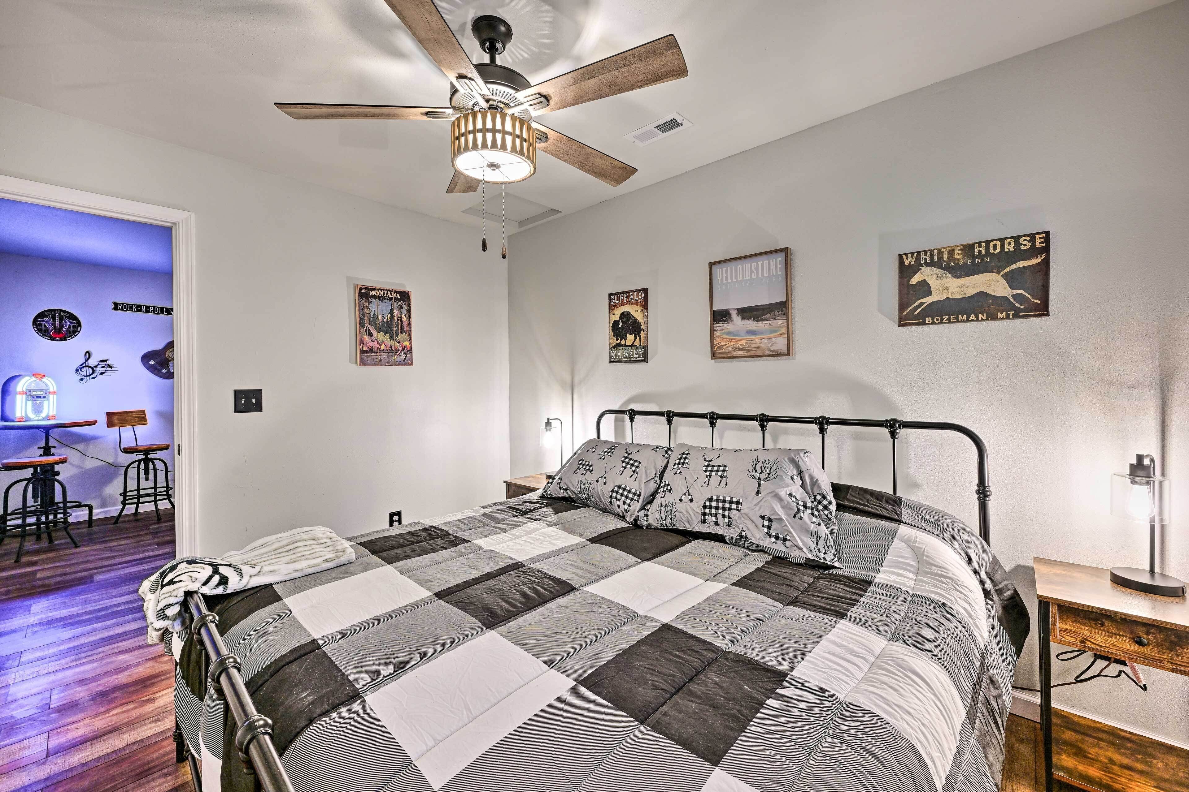 A bedroom with a bed, a ceiling fan, and wall art including a 'White Horse' sign.