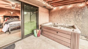 Ein Wellnessbereich mit Whirlpool, Deckenventilator und einem Bett mit gemusterten Betttextilien.