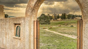 Ein Bogenportal, das in ein grünes Feld mit Schafen führt.