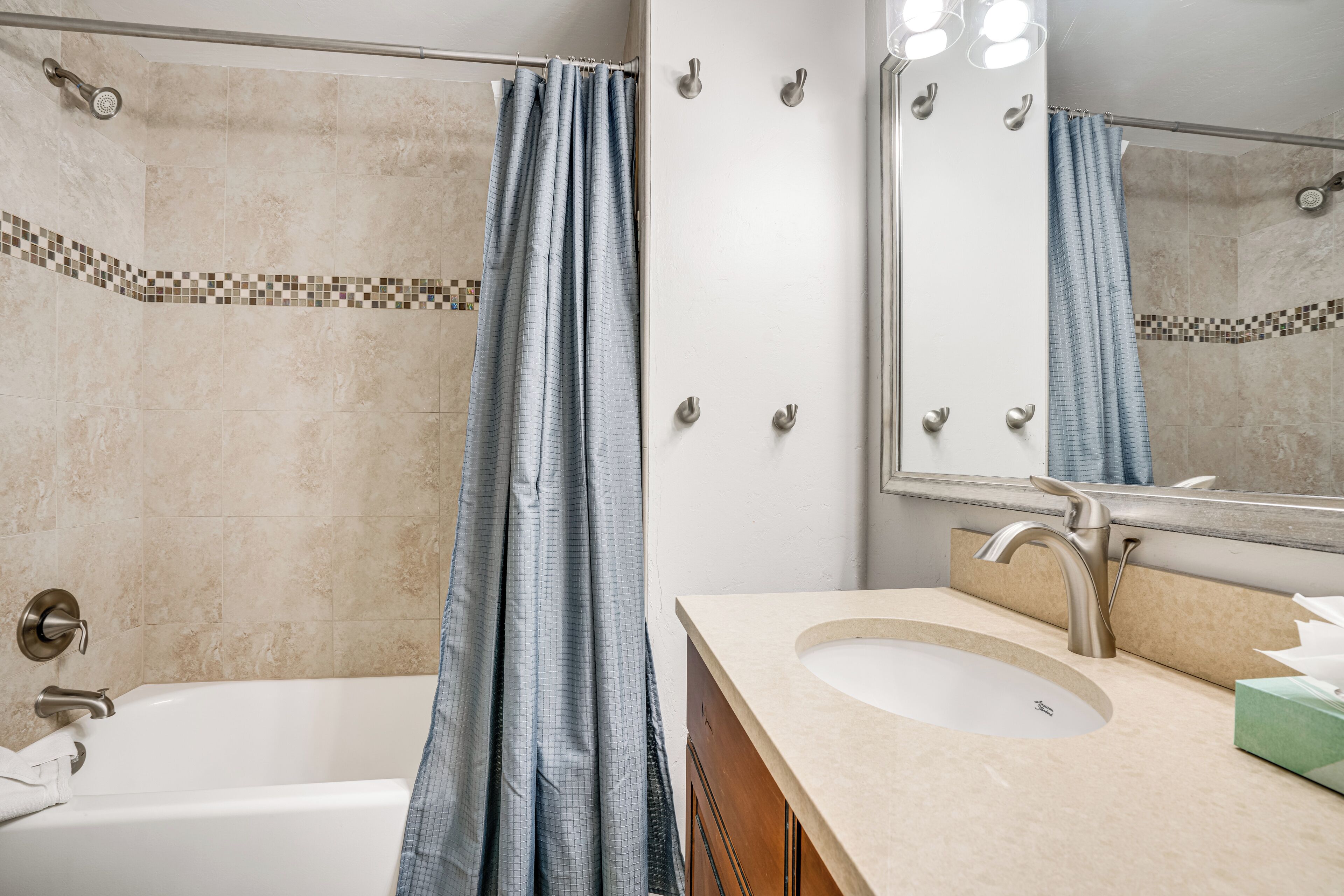 A bathroom with a bathtub, a sink, a mirror, and a shower curtain.