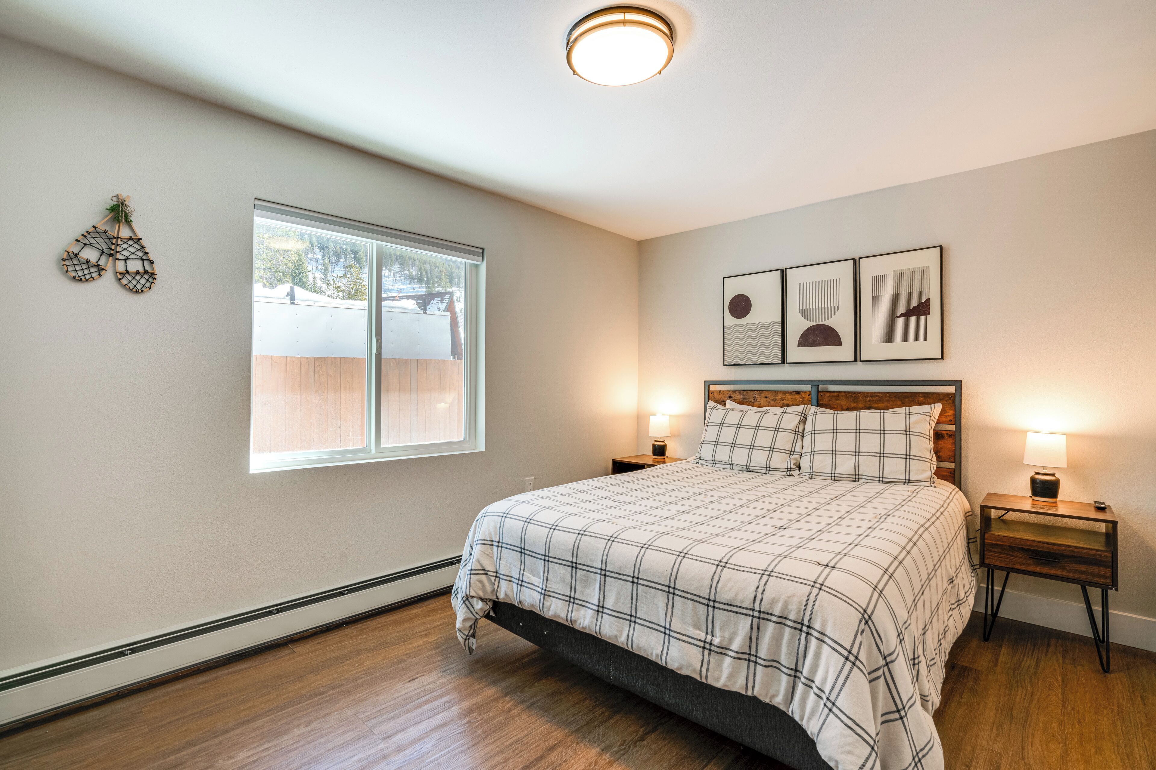 Un dormitorio con una cama grande, dos mesitas de noche, un ventanal y decoración en la pared.