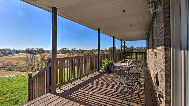 A wooden deck with a railing, a table and chairs, and potted plants. - Family Farmhouse on 160-acre Ranch w/ Hiking Trail (Lawrenceburg)