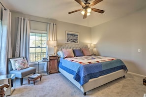 A bedroom with a bed, a chair, a nightstand, a ceiling fan, and a window with curtains. - Family Farmhouse on 160-acre Ranch w/ Hiking Trail (Lawrenceburg)