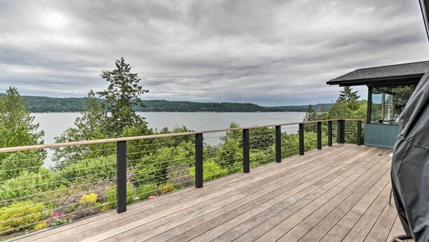 A wooden deck with a metal railing overlooking a lake and forest. - Deck & Sweeping Views: Family Union Home (Union)