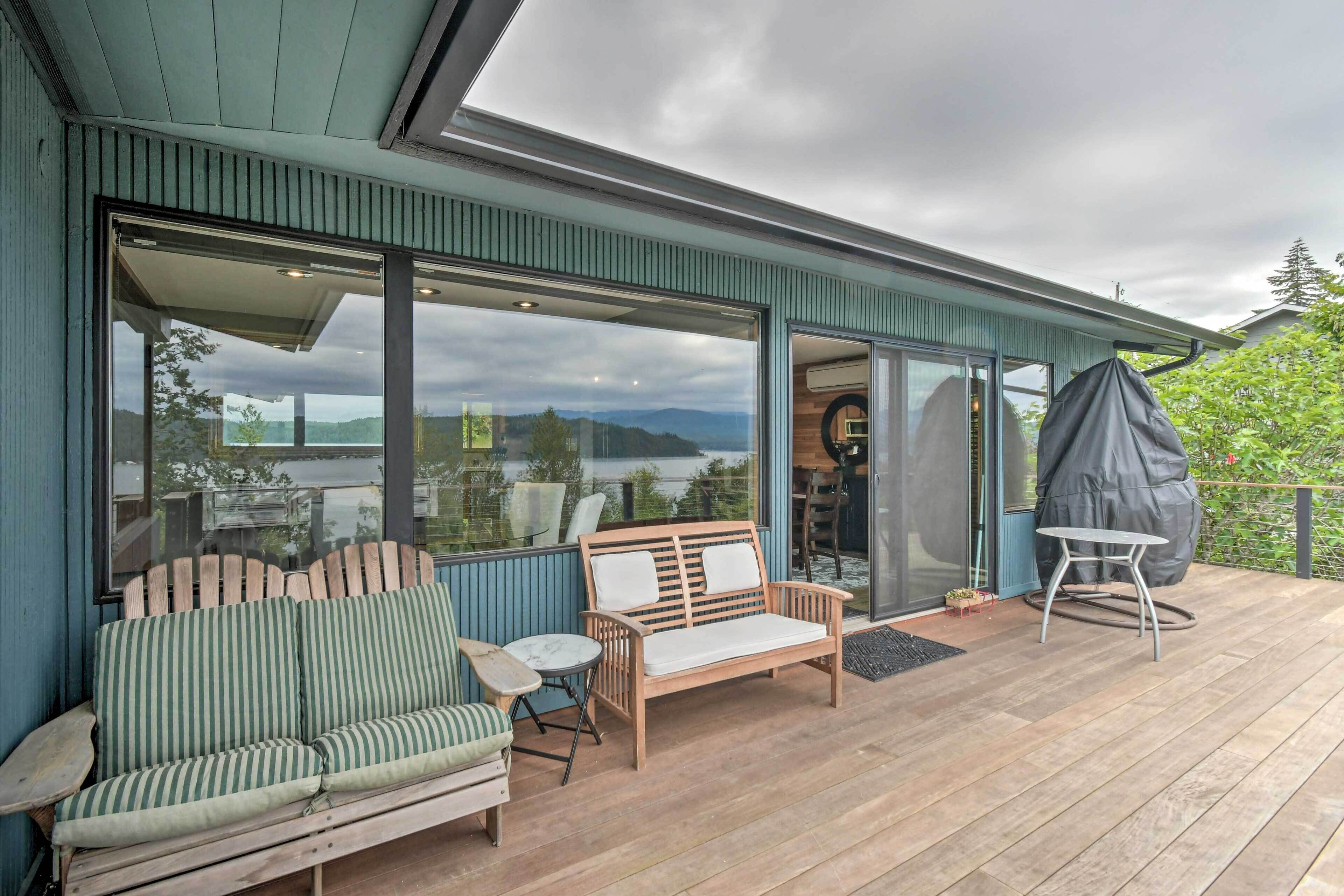 Une terrasse en bois avec un canapé, des chaises et une table, offrant une vue panoramique.