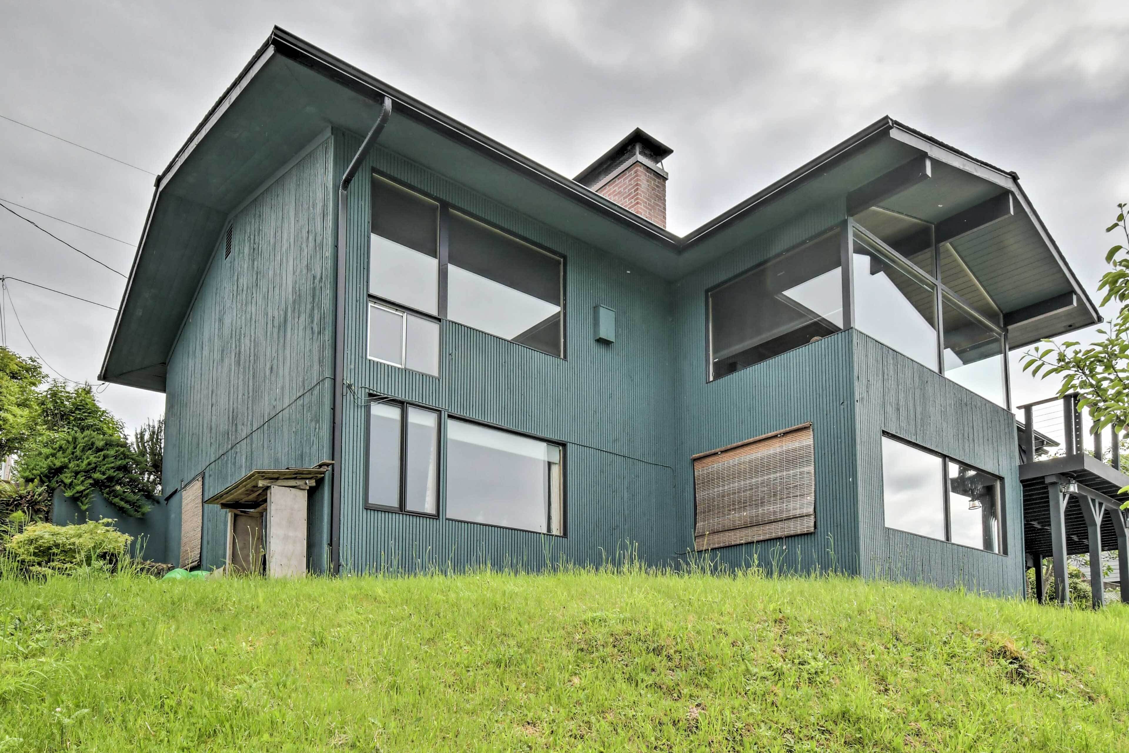 A modern house with a sloped roof, large windows, and a visible chimney.