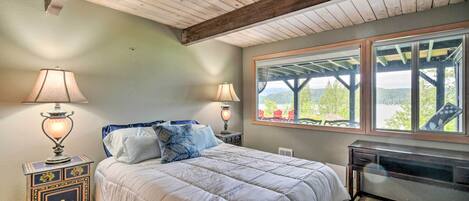 Ein Schlafzimmer mit einem großen Bett, zwei Nachttischlampen, einem hölzernen Kopfteil, einem Fenster mit Aussicht und einem Schreibtisch mit Stuhl.