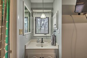 A bathroom with a white sink, a mirror, a window, and a hanging light fixture. - Bear Haven - Renovated Third-floor Escape! (Nellysford)