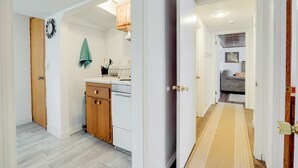 A hallway leading to a kitchen with wooden cabinets and a white countertop. - Pet-friendly Minneapolis Apt Near Shops & Dining! (Spring Lake Park)