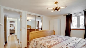 A bedroom with a wooden bed, a large mirror, a ceiling light fixture, and a window with curtains. - Pet-friendly Minneapolis Apt Near Shops & Dining! (Spring Lake Park)