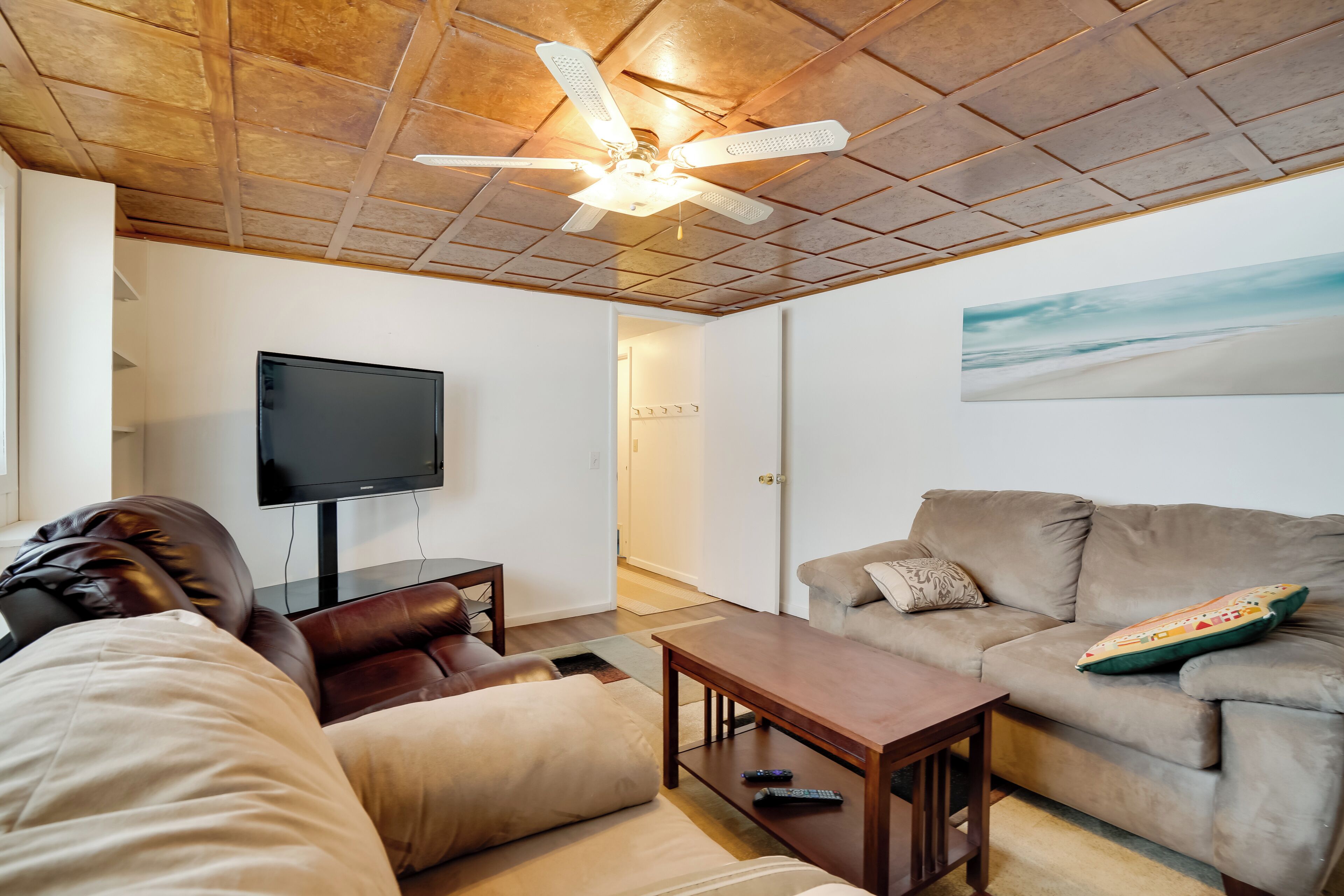 Un soggiorno con ventilatore a soffitto, televisore a schermo piatto, divano e tavolino.