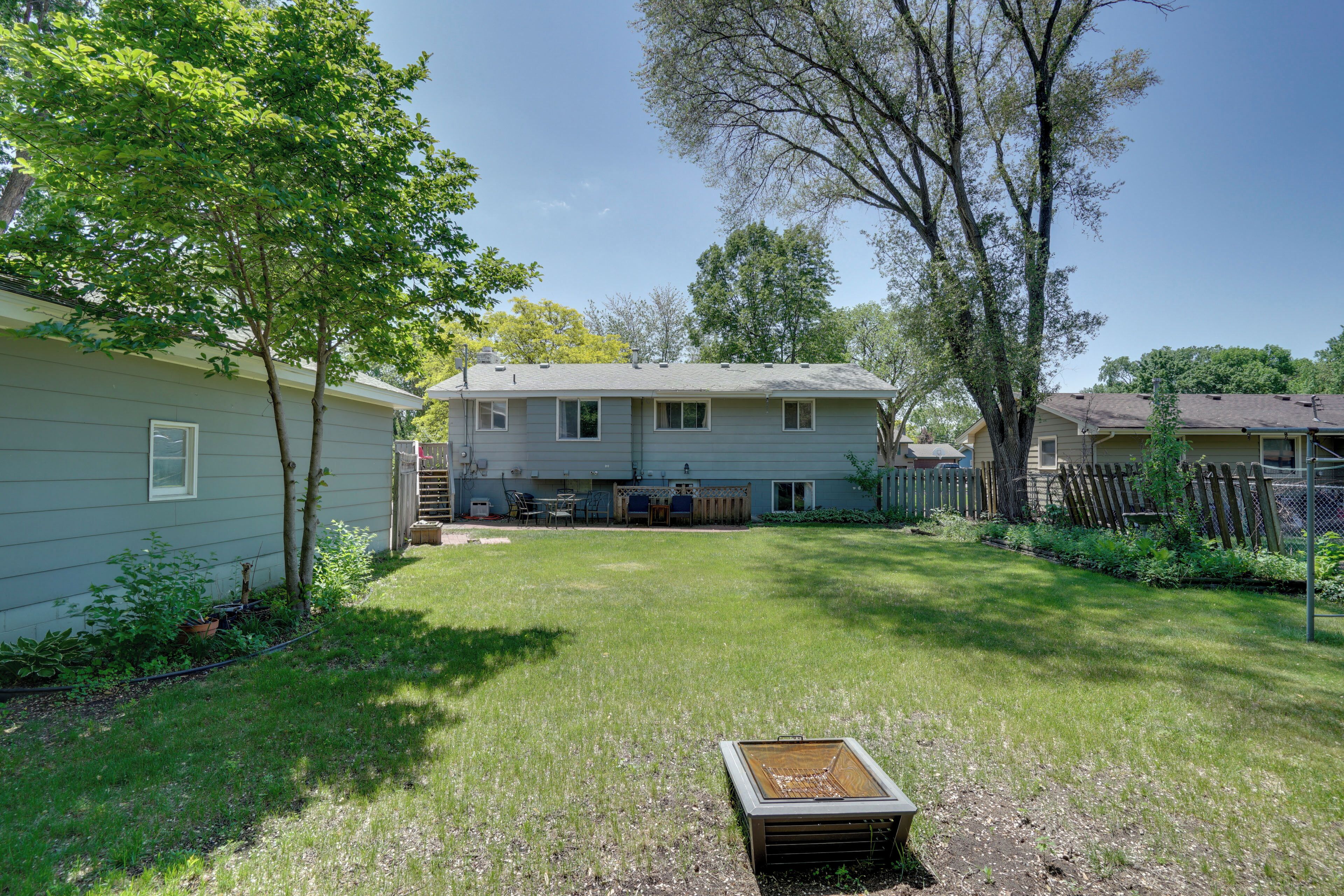 A house with a backyard, a small shed, and a wooden fence.