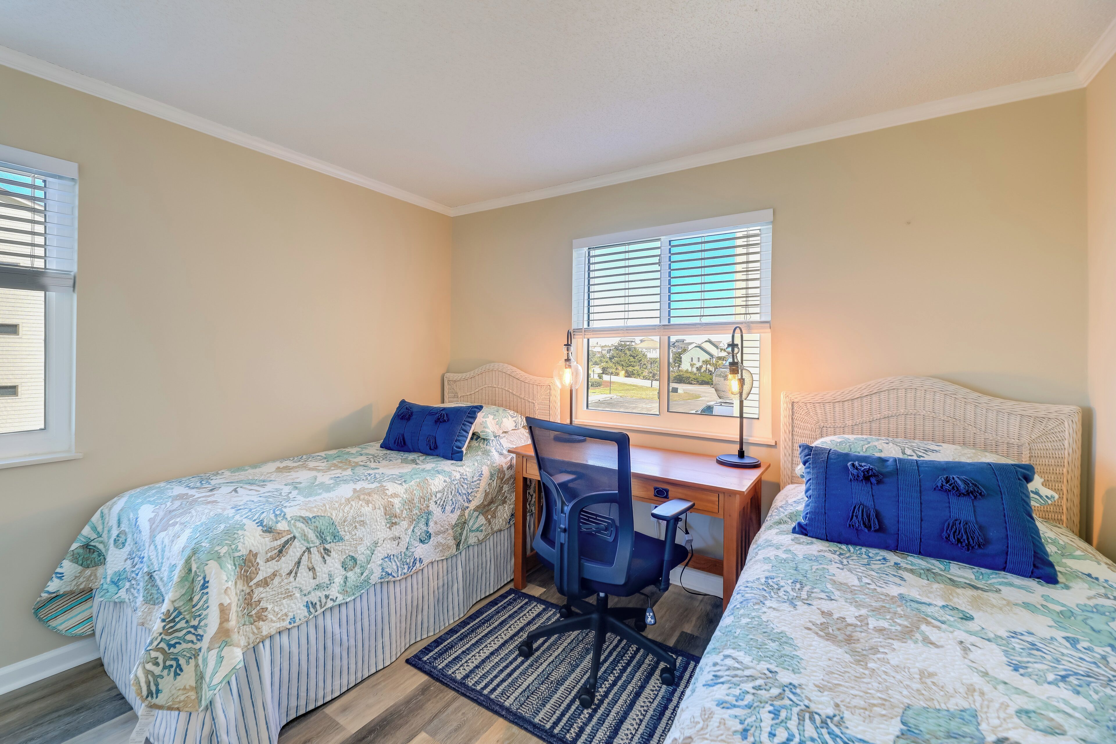 A bedroom with two beds, a desk, and a chair.