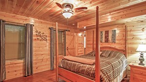 A wooden cabin bedroom with a four-poster bed, a ceiling fan, and a nightstand with a lamp. - Hot Tub & Outdoor Kitchen: Smoky Mountain Cabin (Sevierville)